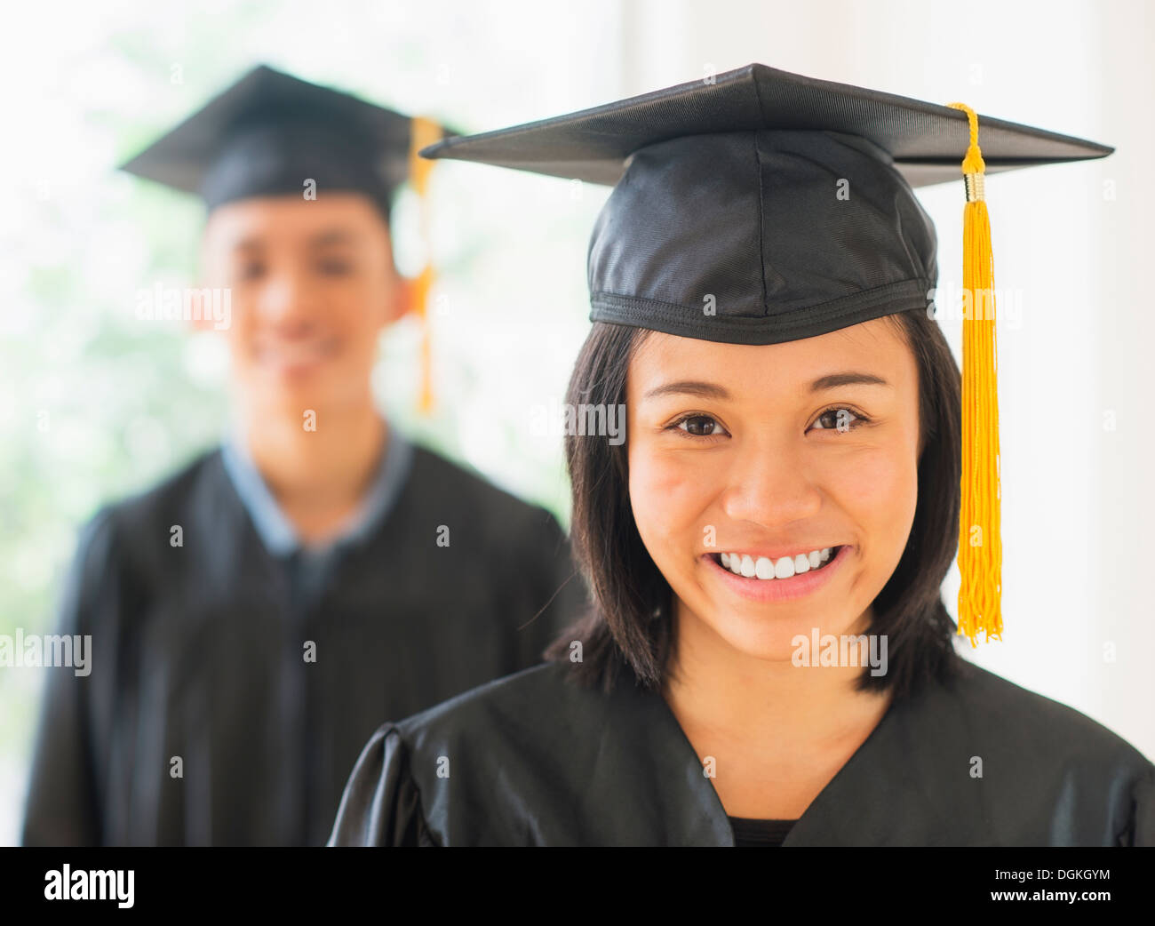 Portrait of young woman and young man wearing graduation gown Stock Photo