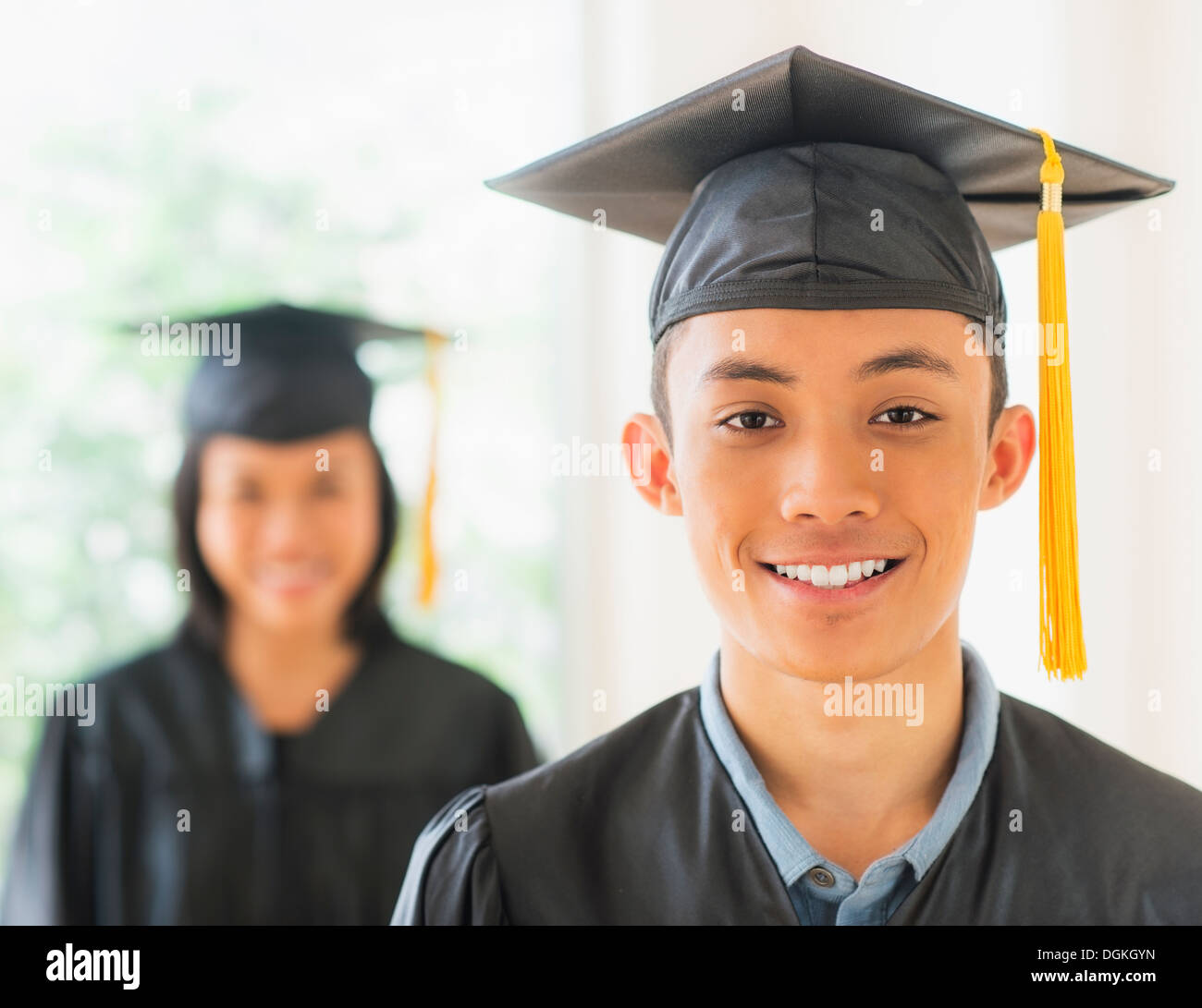 Portrait of young woman and young man wearing graduation gown Stock Photo