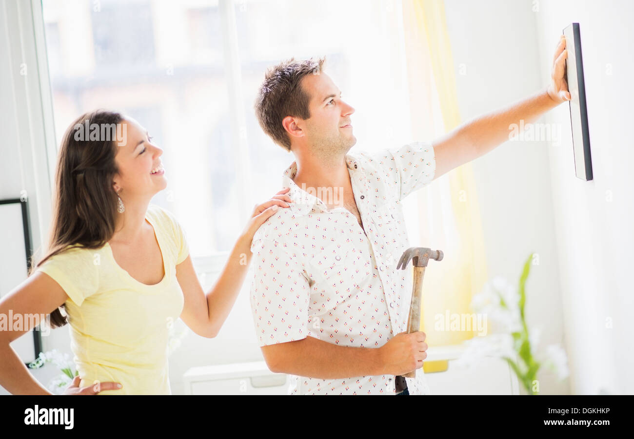 Portrait of happy couple hanging picture Stock Photo - Alamy