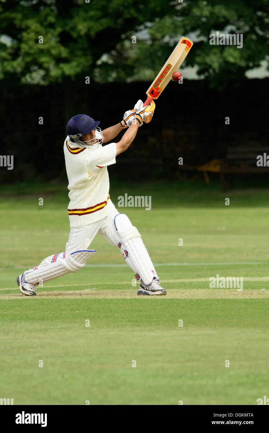 A cricketer in full protective clothing driving the ball towards the viewer. Stock Photo