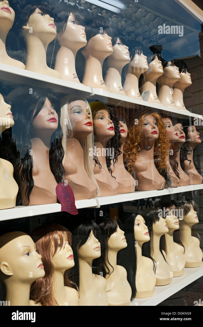 Wigs on display in a shop window. Stock Photo