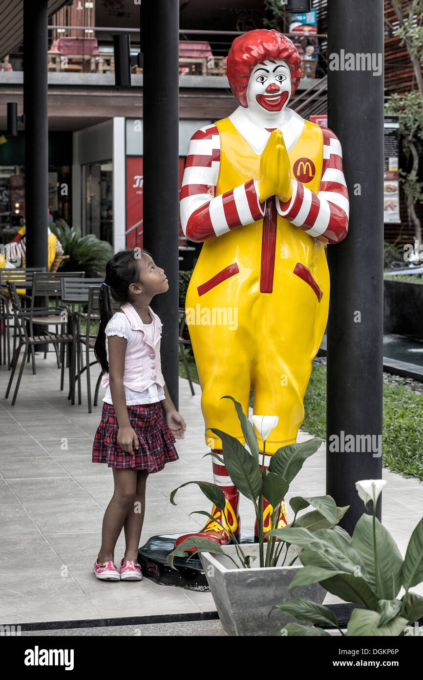 Ronald McDonald. Rural Thai child on her first city visit amazed at the large and colourful statue of Ronald McDonald. Thailand. S. E. Asia Stock Photo