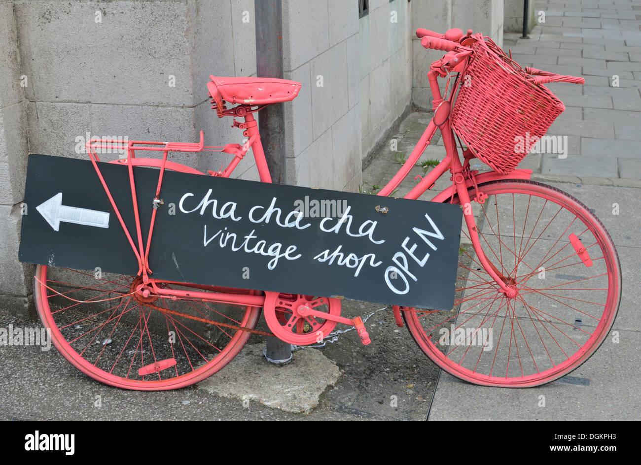A bright pink bicycle advertising Cha Cha Cha vintage shop. Stock Photo