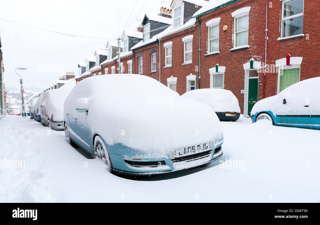 A row of snow covered cars parked along a street in Exeter. Stock Photo
