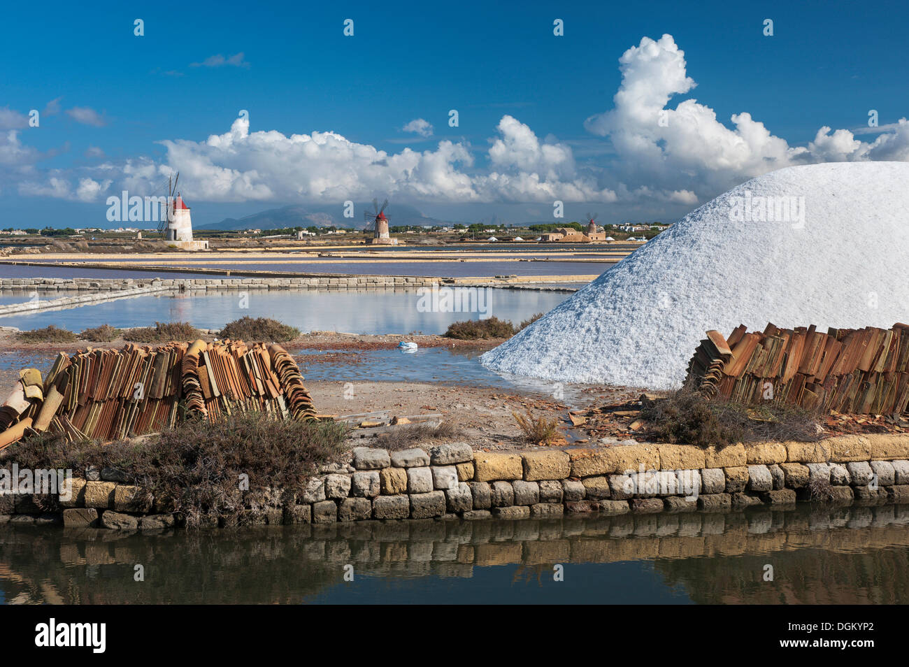Salt stockpile, water basin and channel, windmills at, salt harvest in the Salinas, bei Trapani, Sicily, Italy Stock Photo