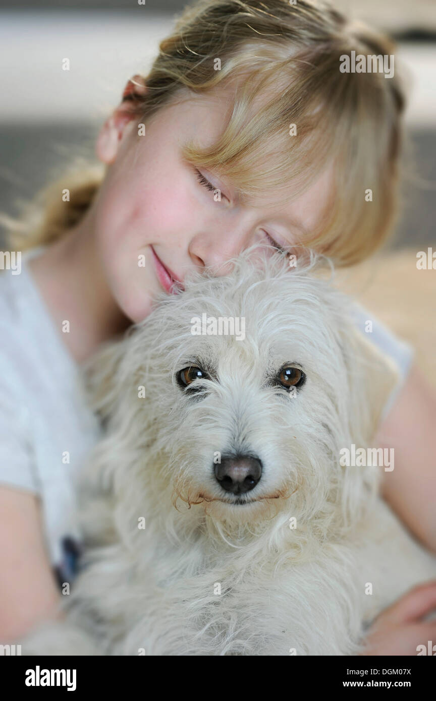 Girl, 9, cuddling with a young mixed-breed dog Stock Photo