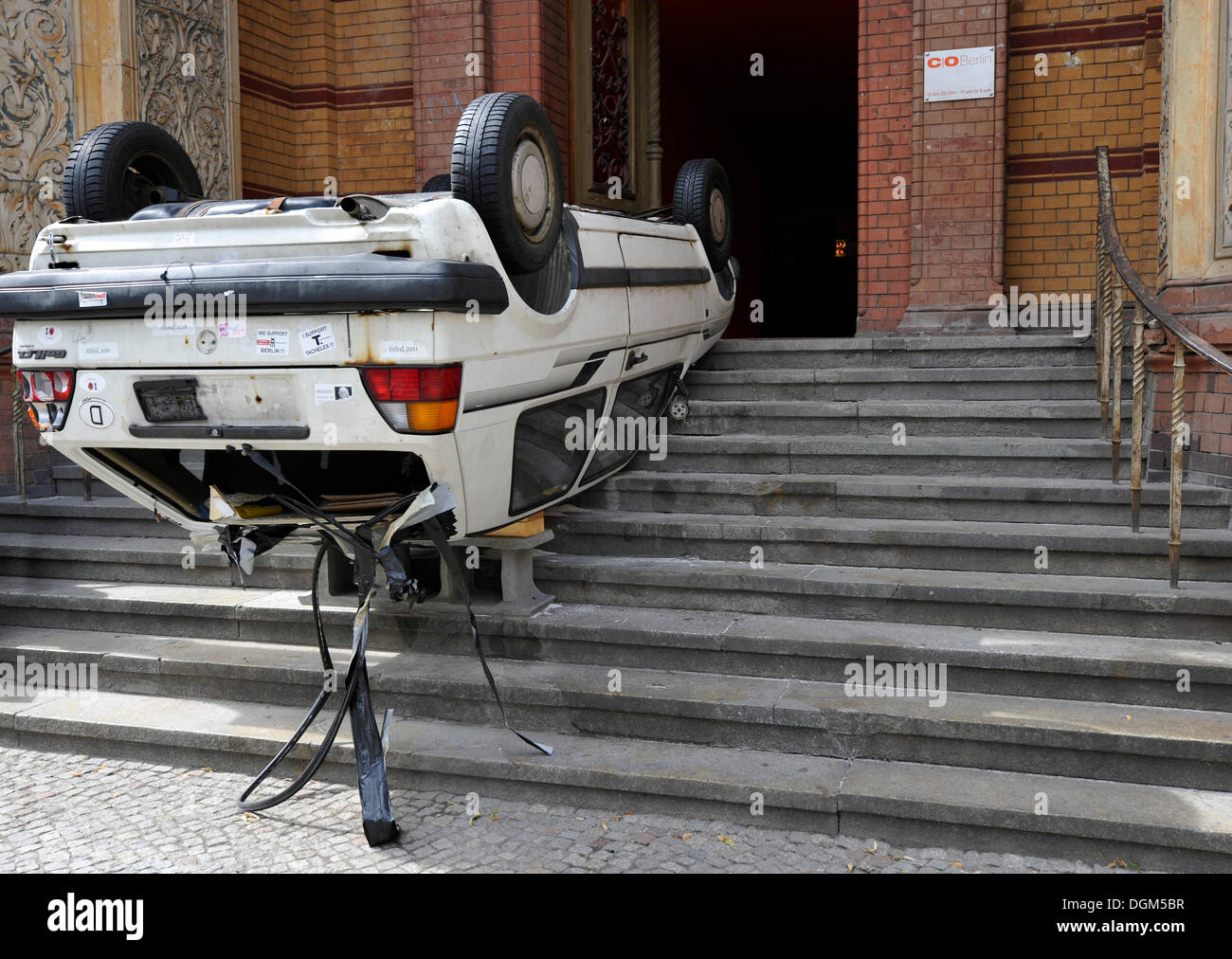 Art and culture, old car wreak on its roof in the front entrance of the Altes Postfuhramt, Old Royal Post Office, Berlin Stock Photo
