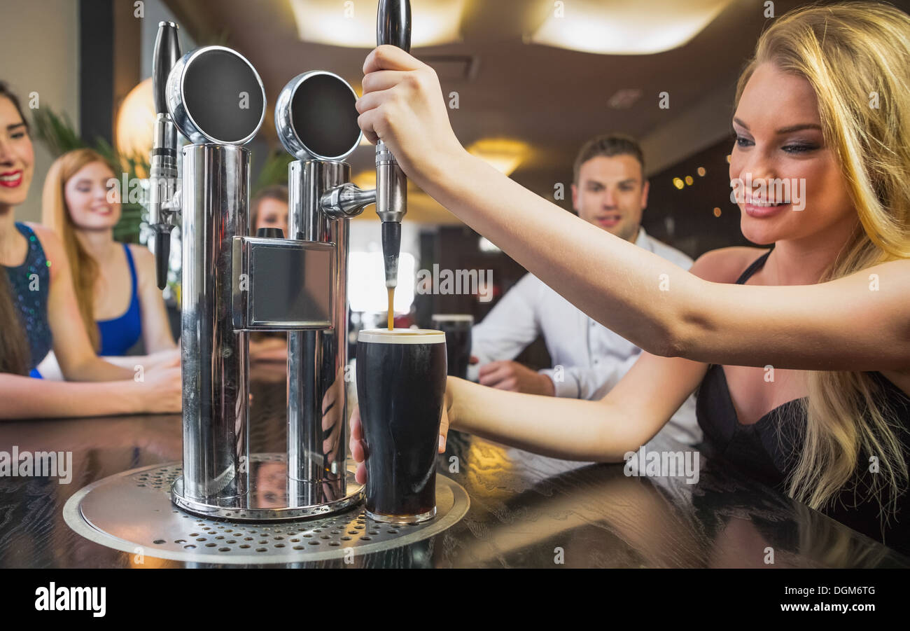 Attractive woman pulling a pint of stout Stock Photo