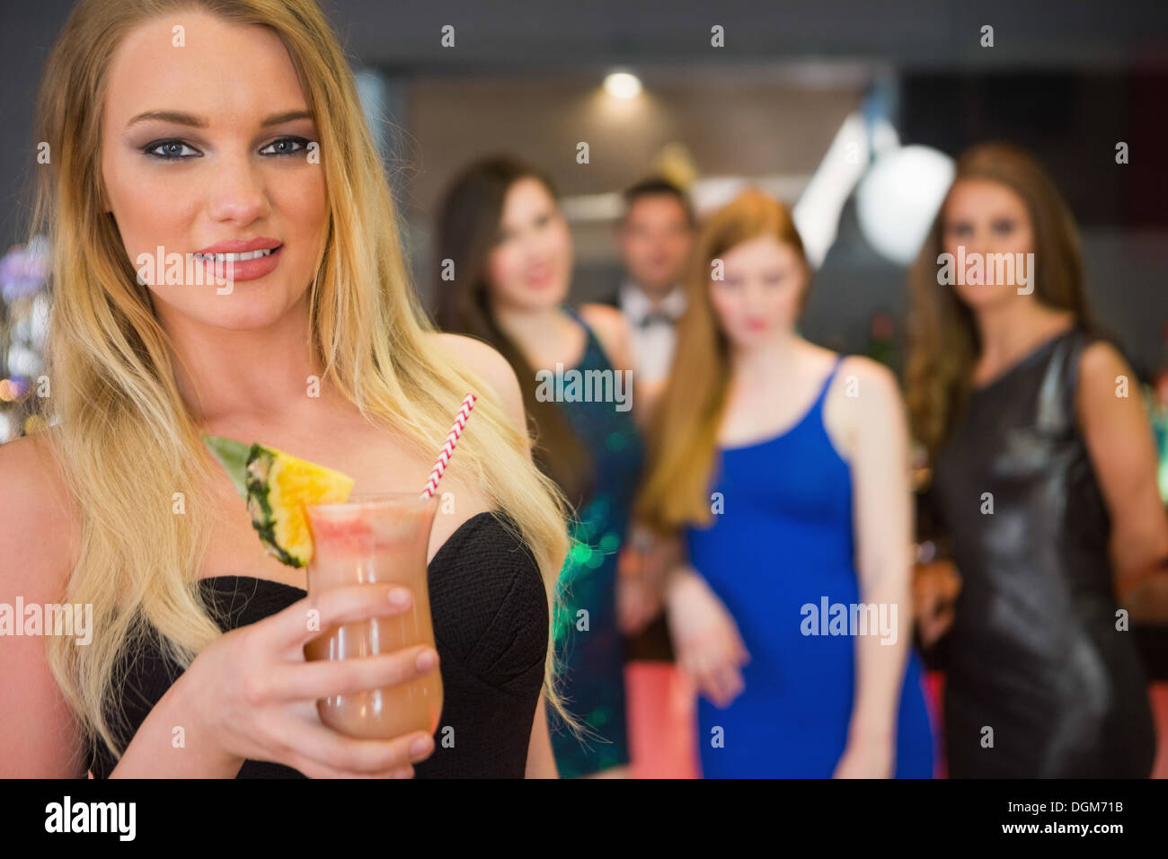 Blonde woman standing in front of her friends holding cocktail Stock Photo