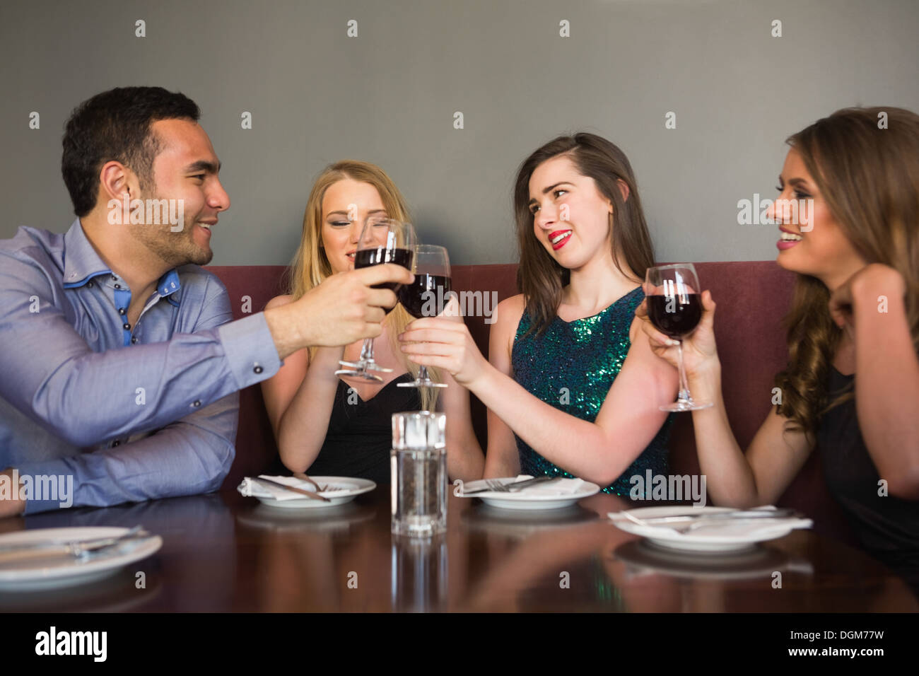 Friends clinking red wine glasses at a bar Stock Photo