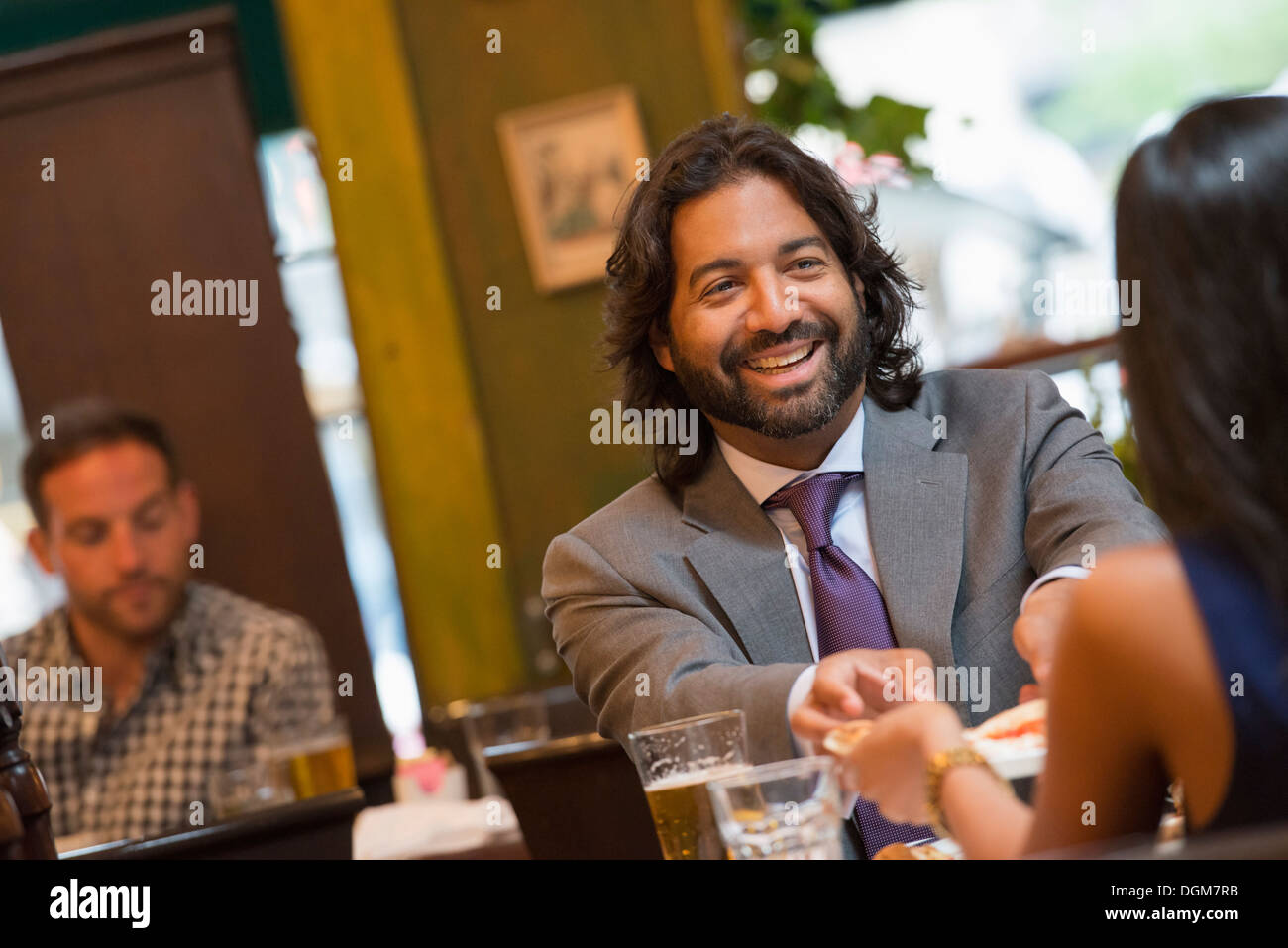 Business people. Two people seated at a table holding hands. A man in the background. Stock Photo