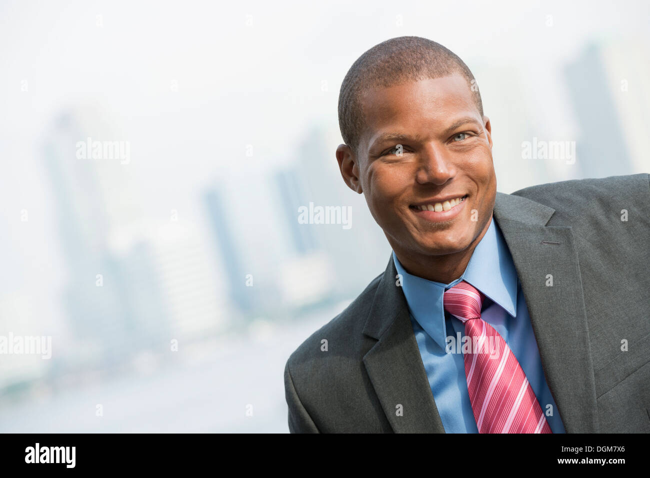 A young man in a business suit with a blue shirt and red tie. On a city ...