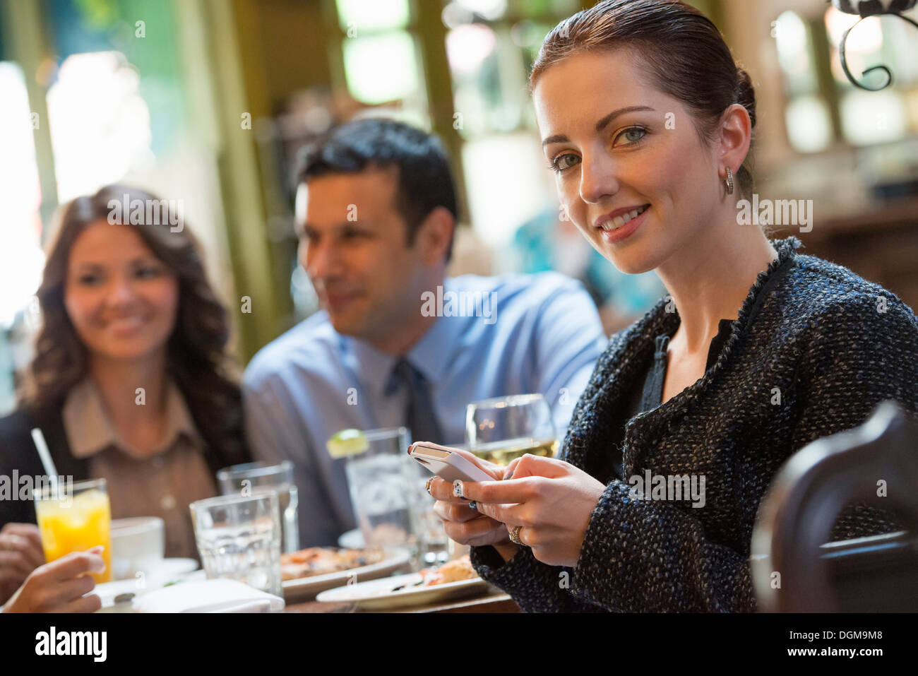 Business people. Three people around a cafe table, one woman turning
