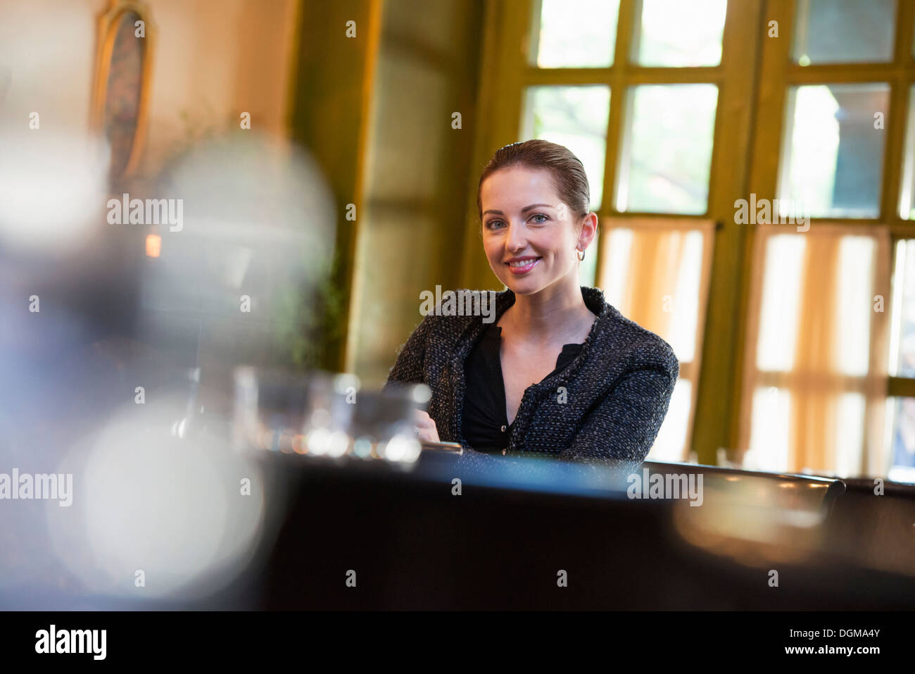 Business people outdoors. A woman sitting alone at a table in a coffeeshop or restaurant. Stock Photo