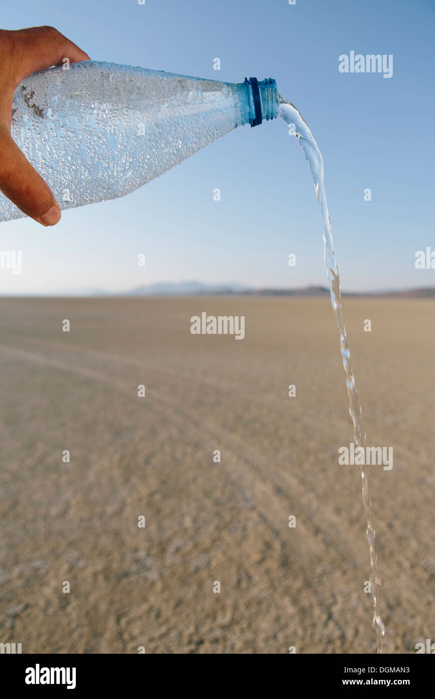 The landscape of the Black Rock Desert in Nevada. A bottle of water being poured out. Filtered mineral water. Stock Photo