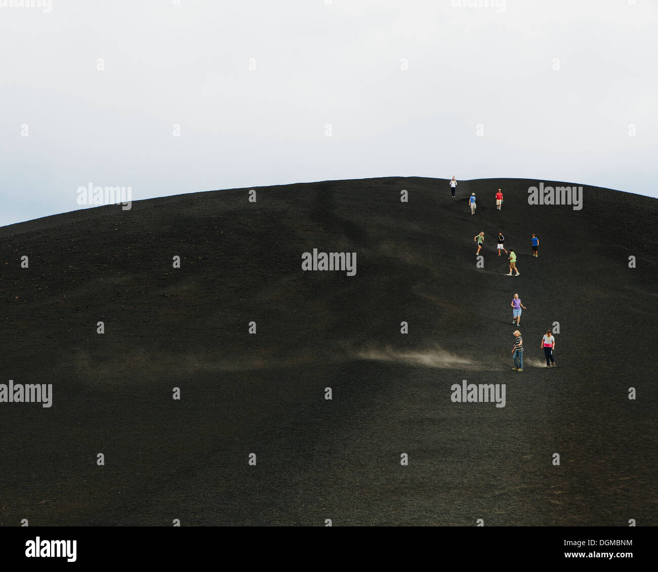 A black volcanic cone hillside in Craters of Moon national monument preserve in Butte County Idaho People walking on slope. Stock Photo