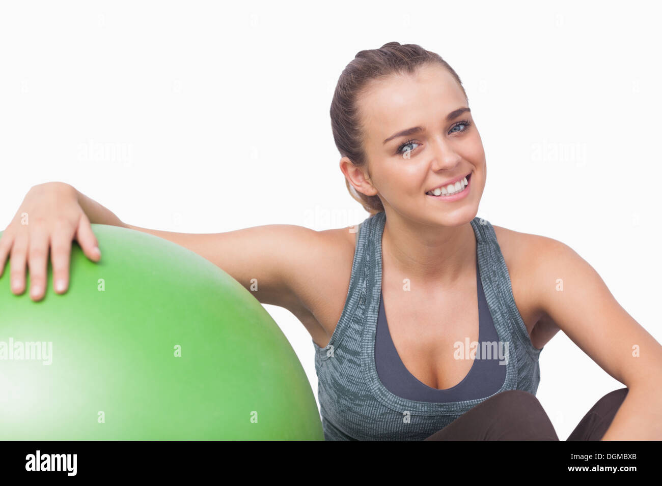 Smiling sporty woman sitting next to a fitness ball Stock Photo