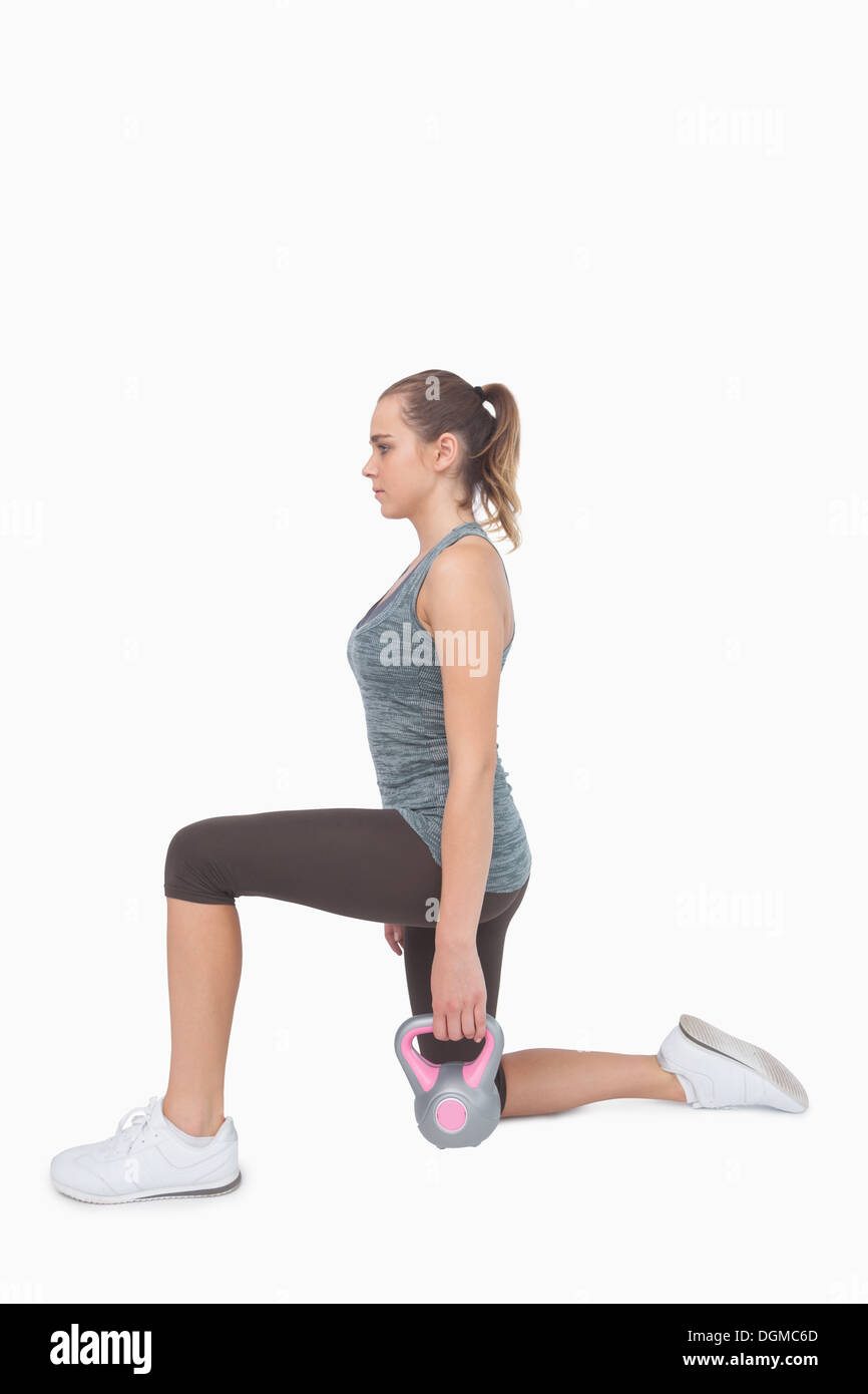 Blonde woman training with kettle bell while lunging Stock Photo