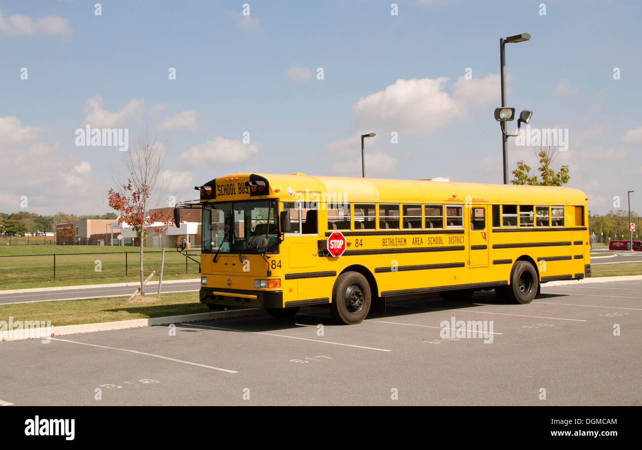 American school bus with school in background Bethlehem, Nazareth, Pennsylvania, USA. Stock Photo