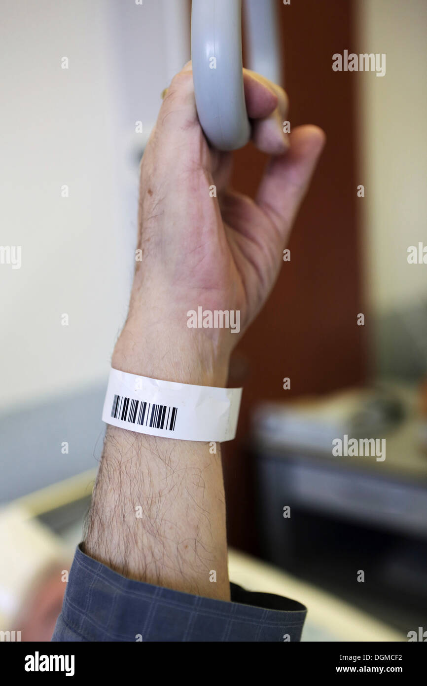 Senior with a barcode wristband in a hospital, detail of a hand holding a hand grip on a bed Stock Photo