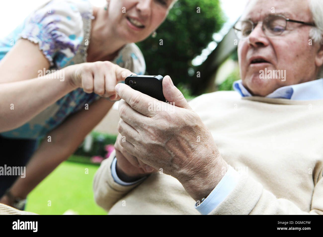 Young woman explaining to a senior citizen how to use a smartphone Stock Photo
