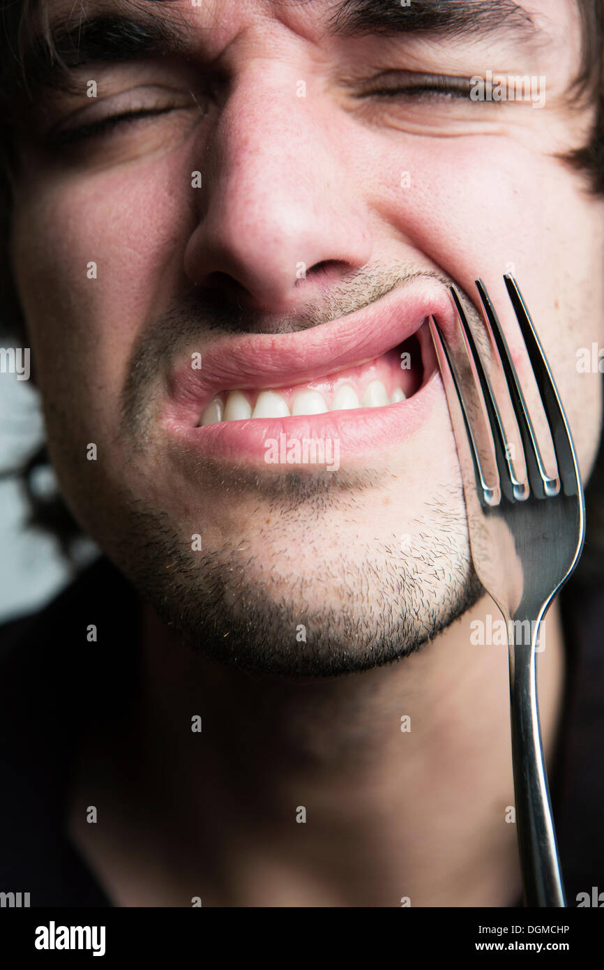 Young man with a fork in his lip, Germany Stock Photo