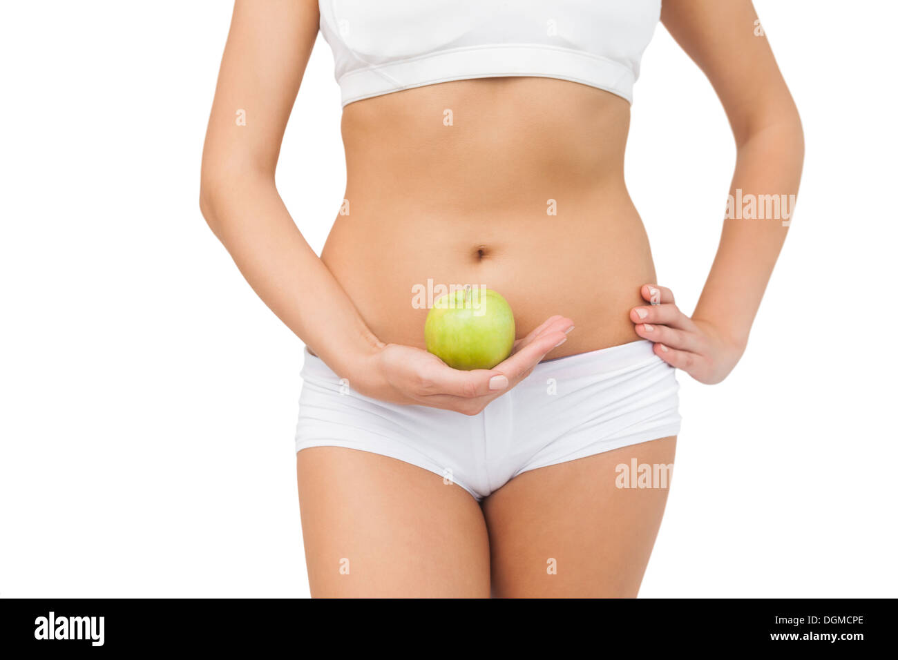 Young slim woman wearing a sports bra holding a green apple Stock Photo
