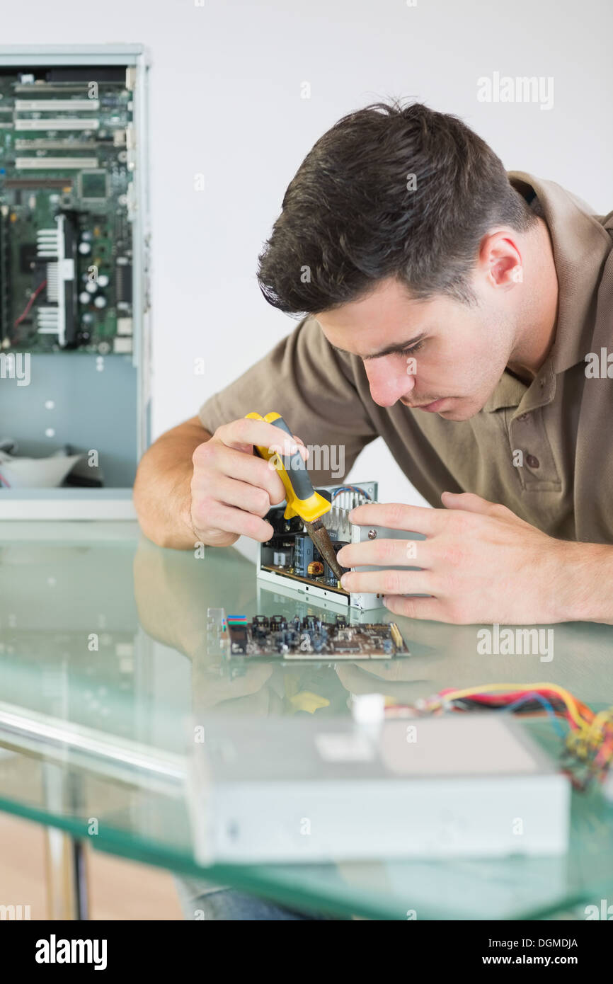 Handsome focused computer engineer repairing hardware with pliers Stock