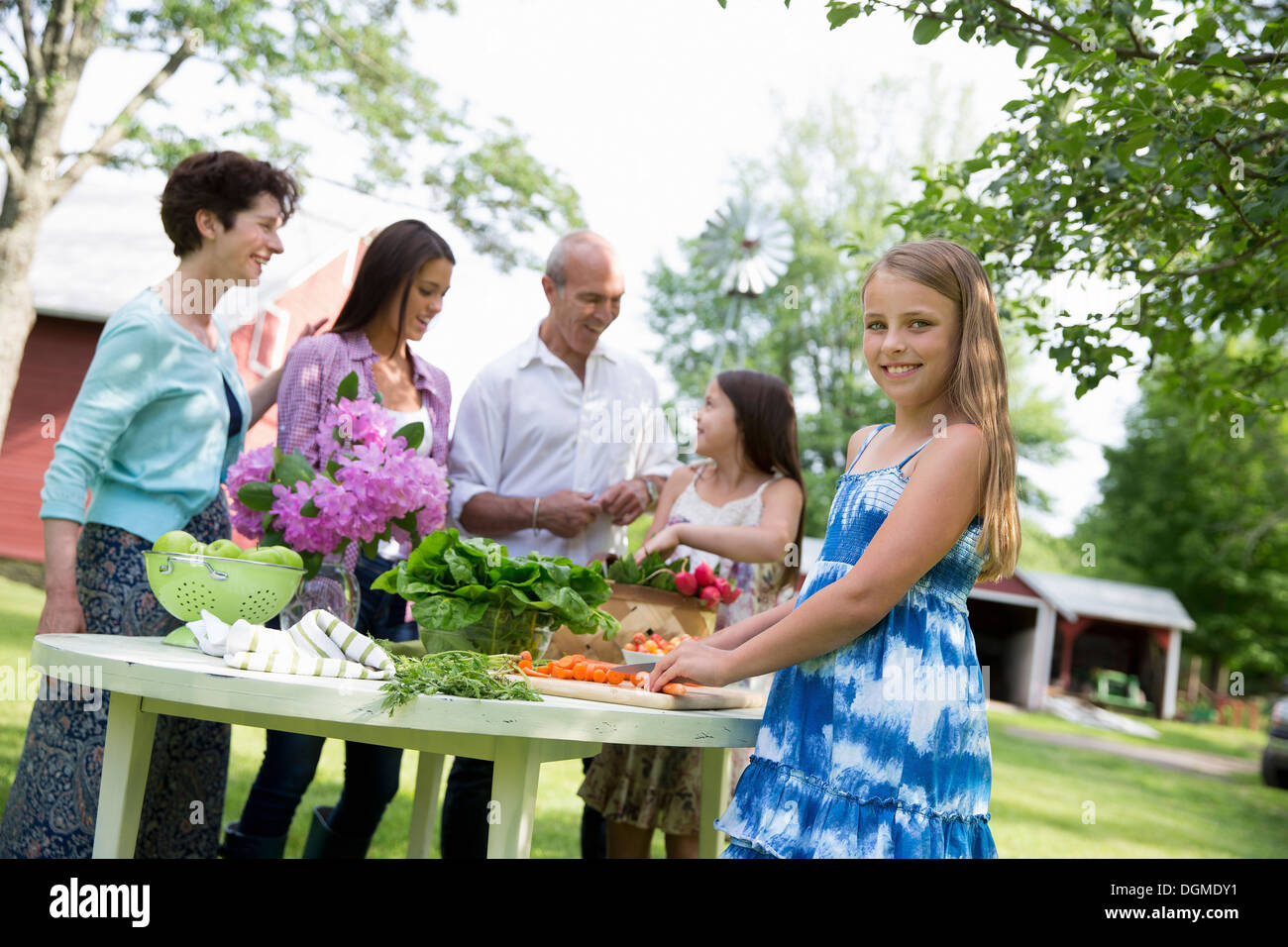Family party table salads fresh fruits vegetables Parents children. Two girls, one young woman mature couple Stock Photo