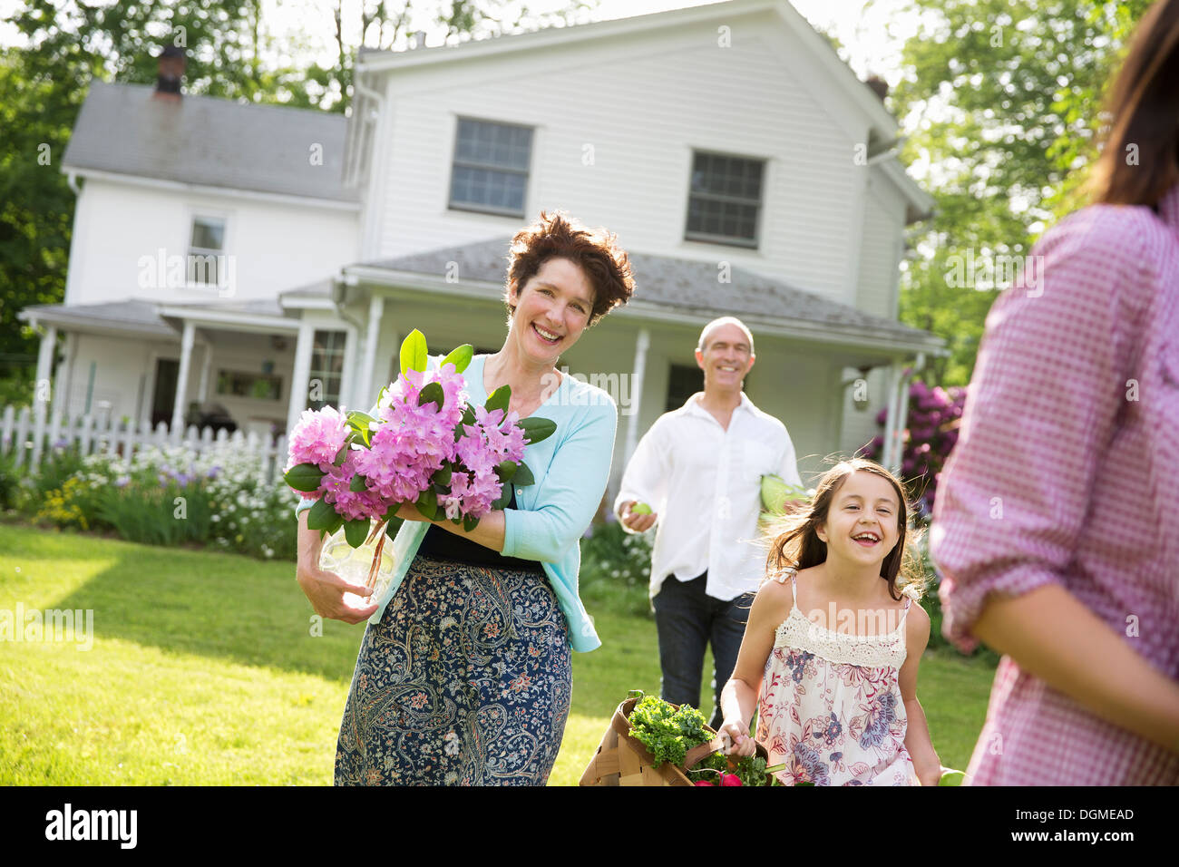 Family party. Parents and children carrying flowers, fresh picked vegetables and fruits. Preparing for a party. Stock Photo