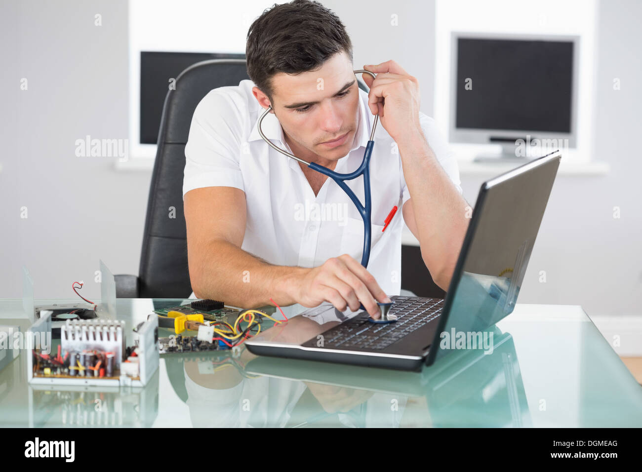 Handsome stern computer engineer examining laptop with stethoscope Stock Photo