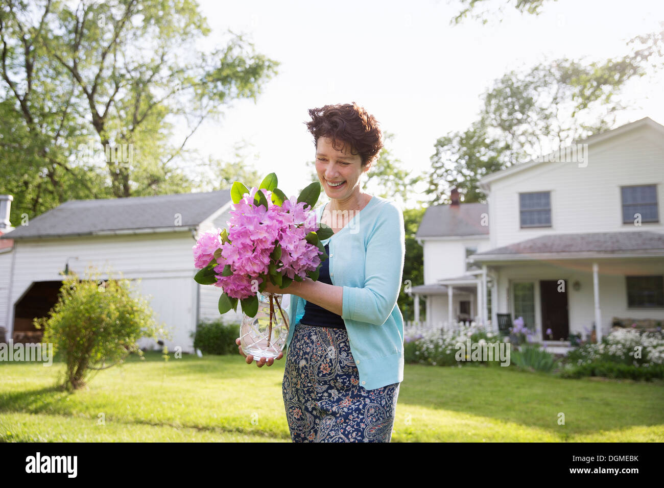 Family party. A woman carrying a large bunch of rhododendron flowers, smiling broadly. Stock Photo