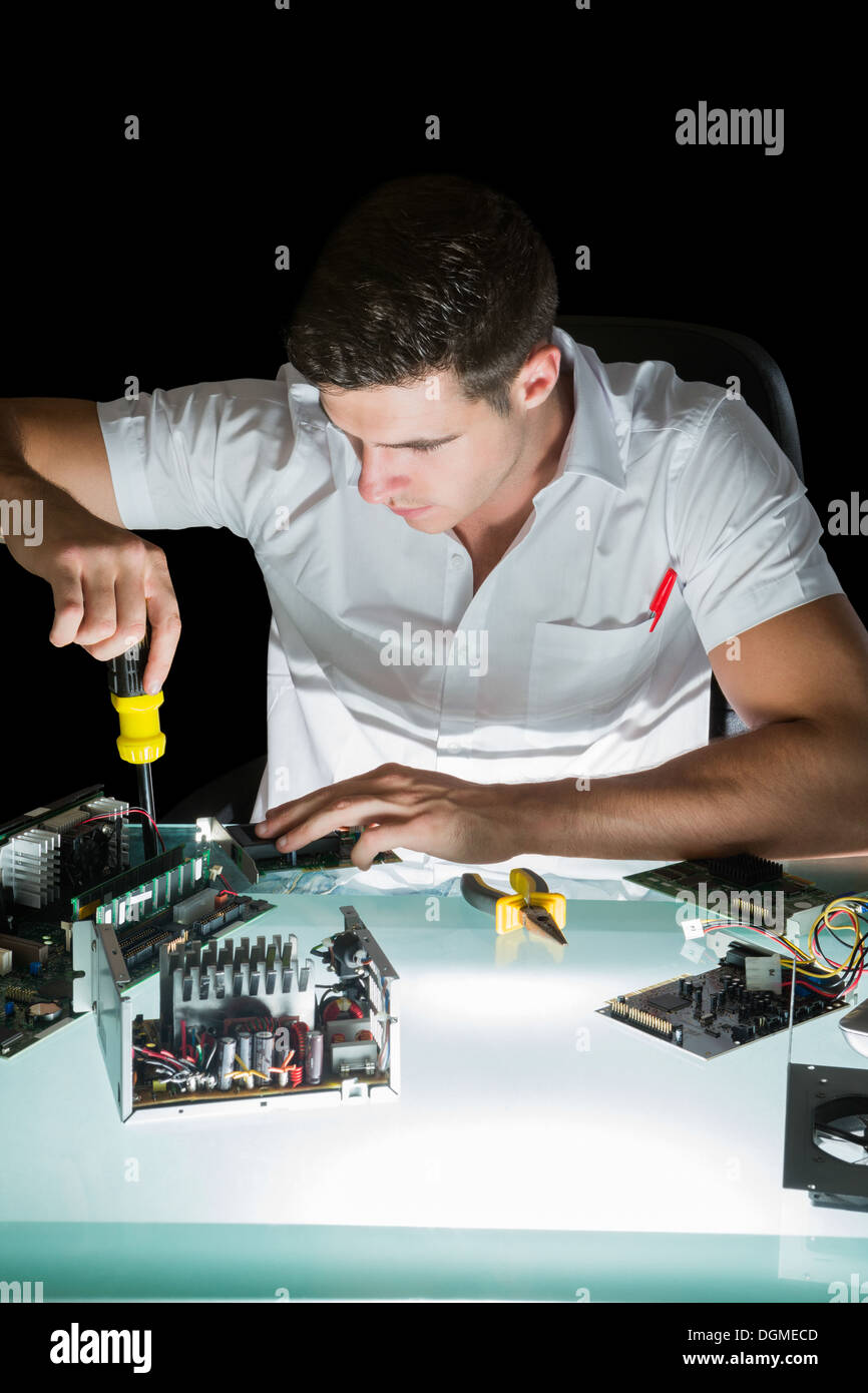 Handsome computer engineer working by night with screw driver Stock Photo