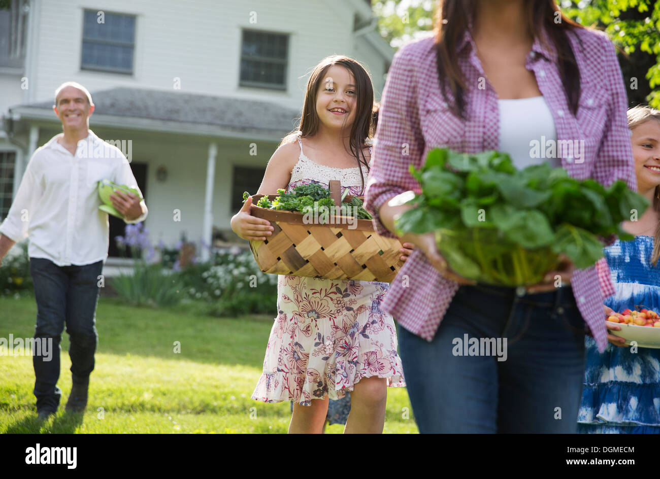 Family party. Parents and children carrying flowers, fresh picked vegetables and fruits. Preparing for a party. Stock Photo