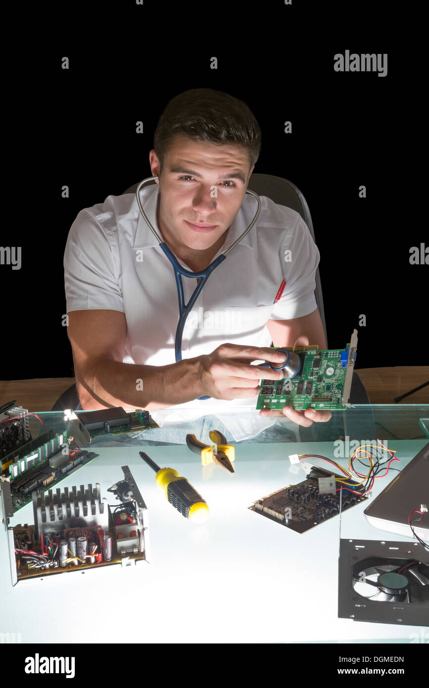 Smiling computer engineer examining hardware with stethoscope by night ...
