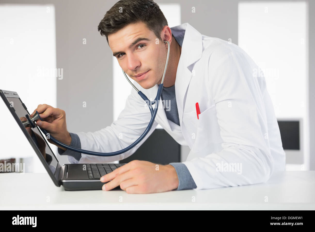 Attractive smiling computer engineer examining laptop with stethoscope ...