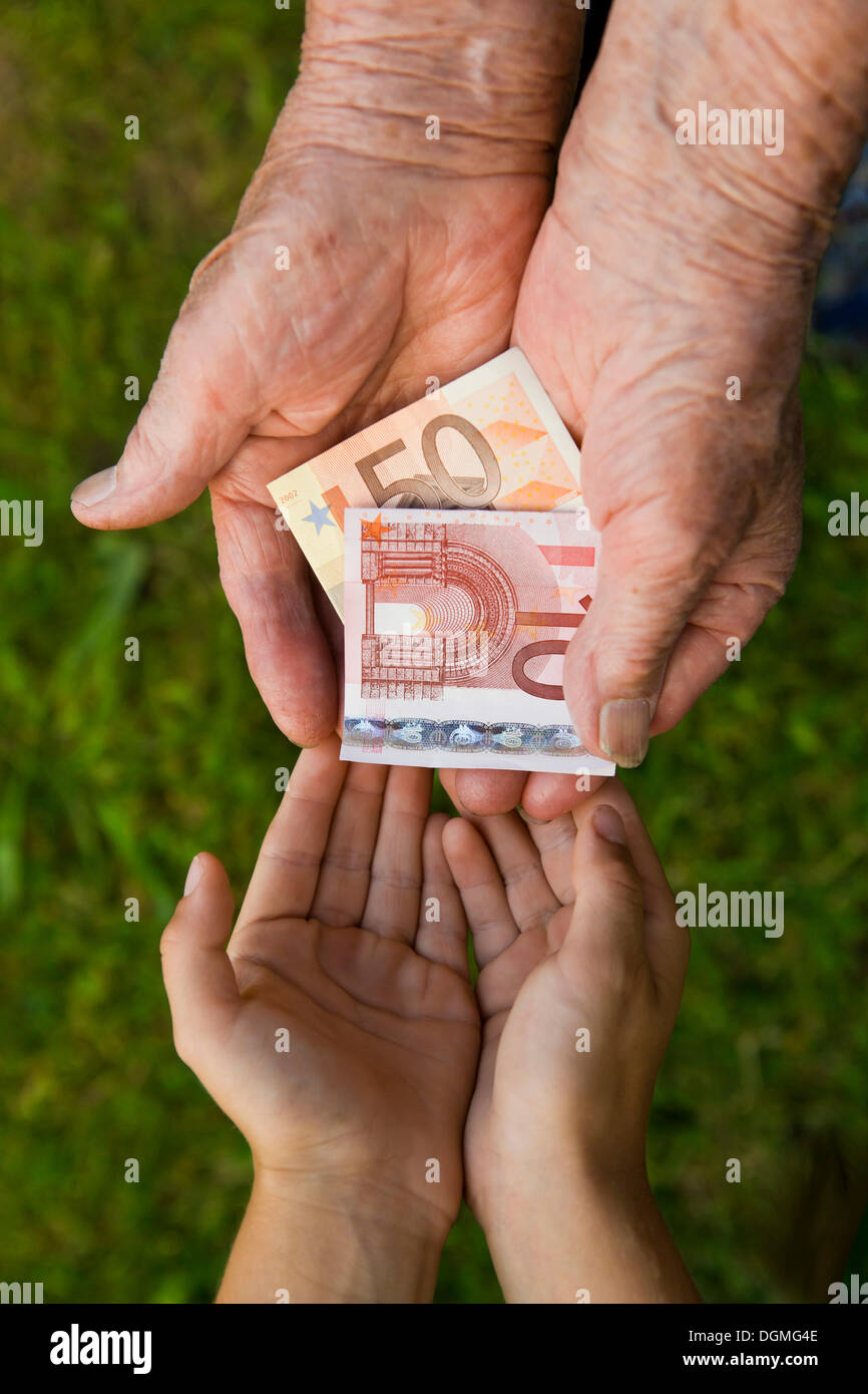 Elderly woman giving a child money, euro banknotes Stock Photo