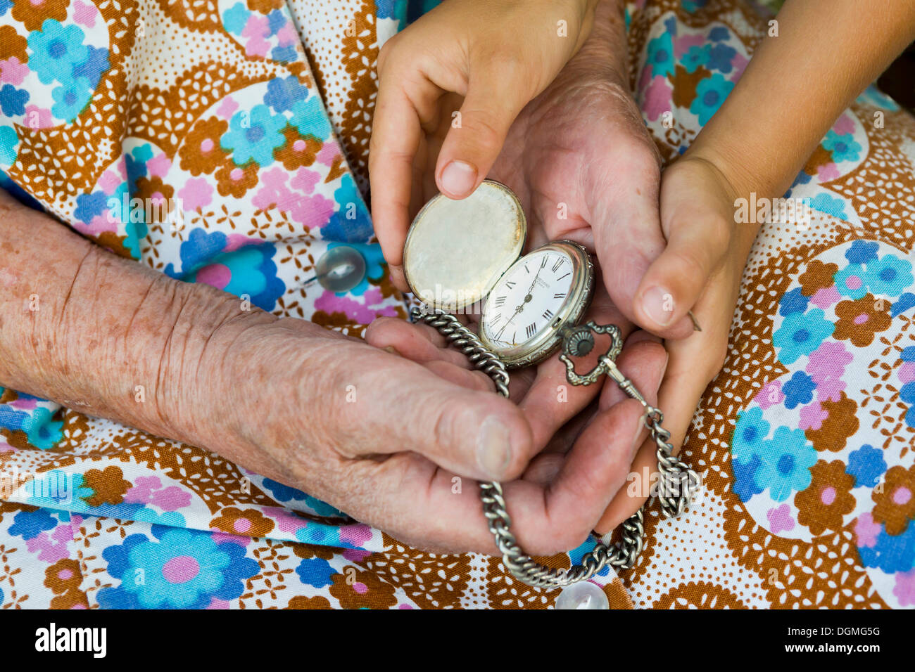 Elderly woman and a child holding an old pocket watch in their hands Stock Photo