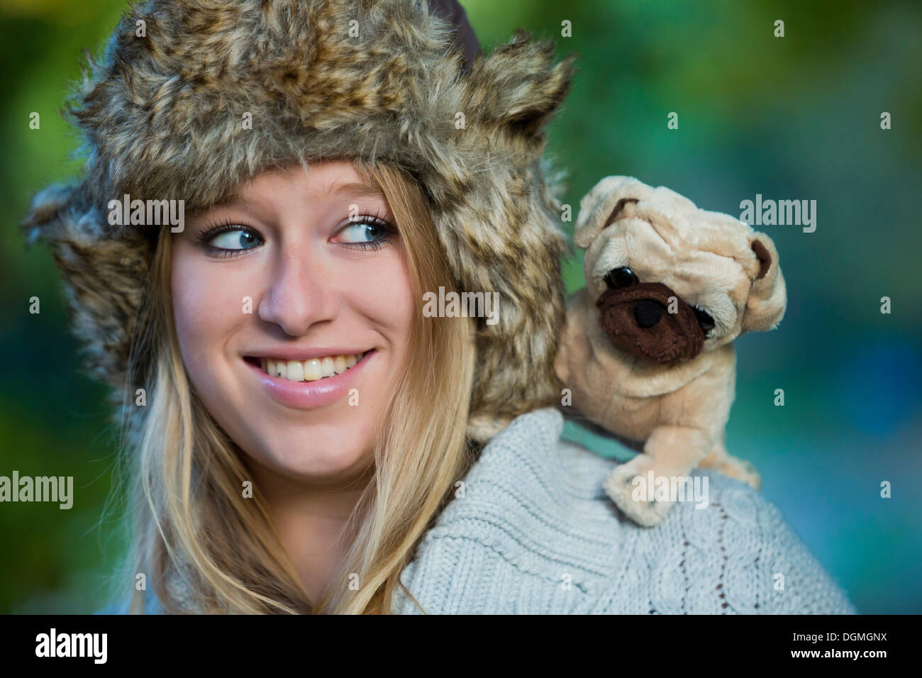 Young woman wearing a fur hat with a plush pug on her shoulder Stock Photo