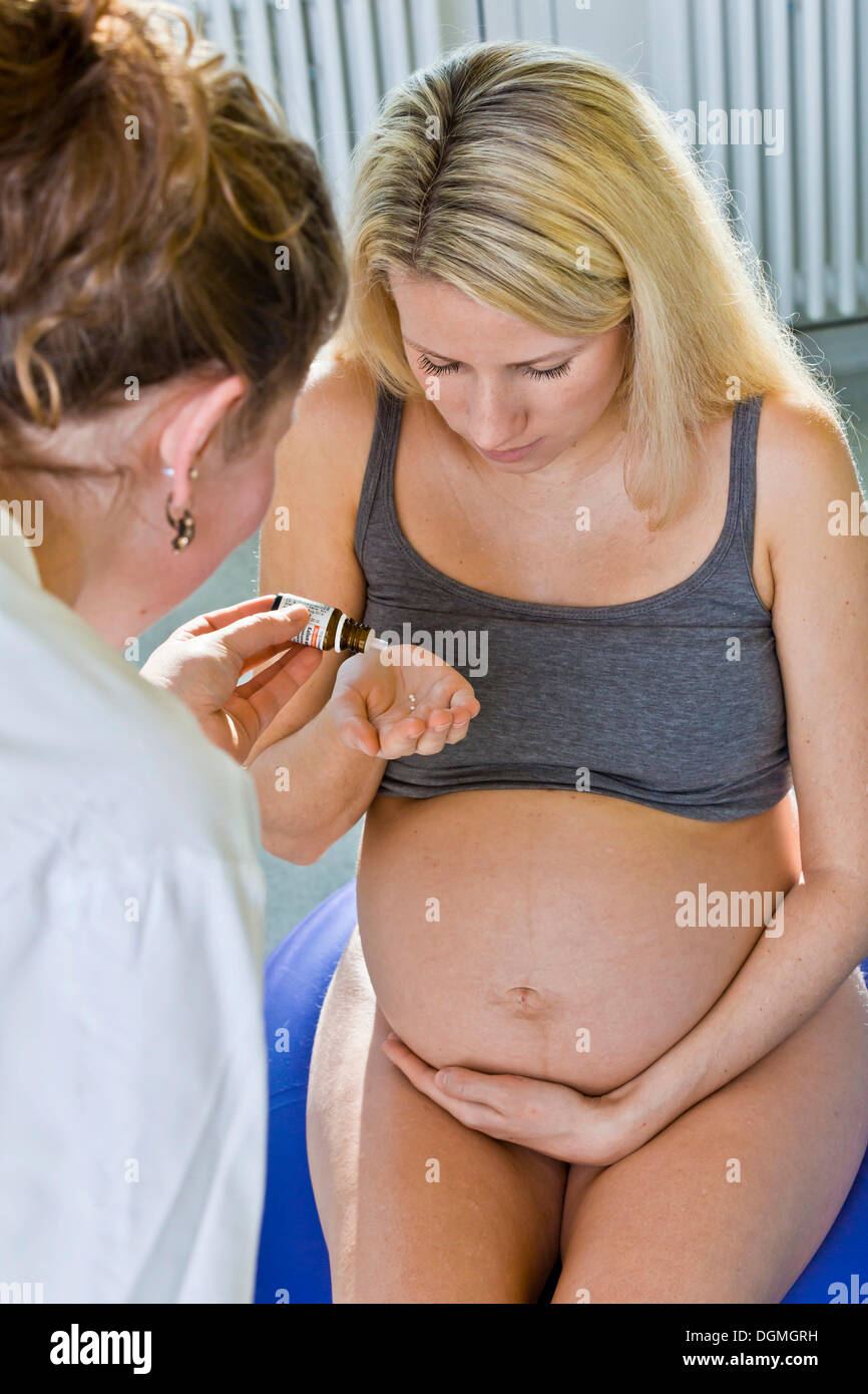 Pregnant woman recieving homeopathic medicine from her midwife during delivery, Germany Stock Photo