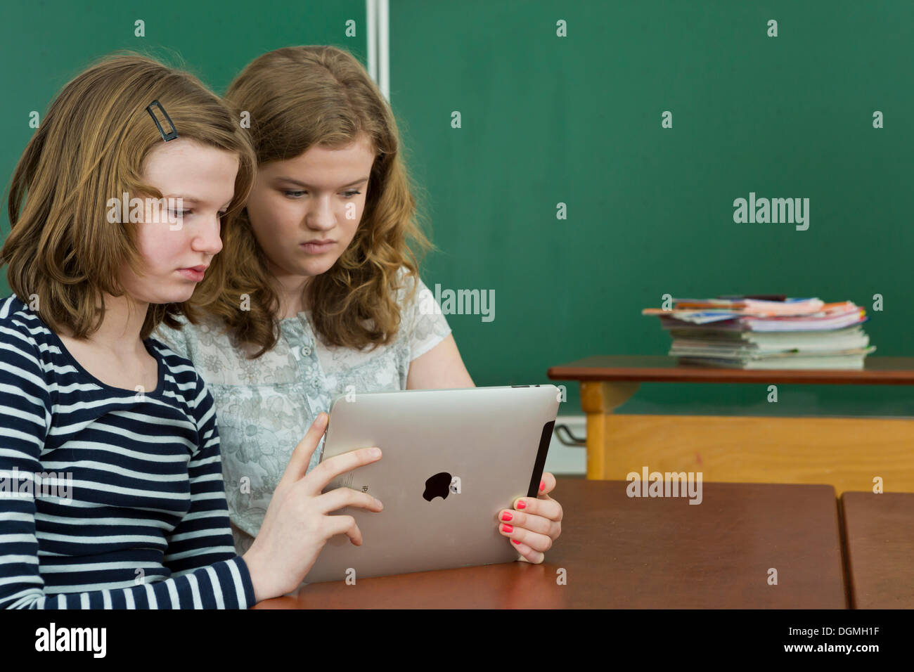Two schoolgirls in the classroom using a tablet PC, Germany Stock Photo