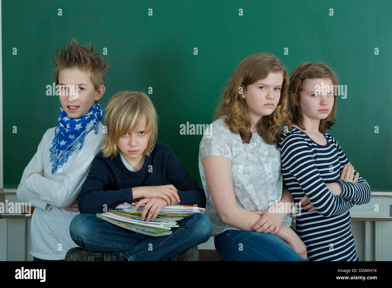 Four grumpy school children in a classroom, Germany Stock Photo