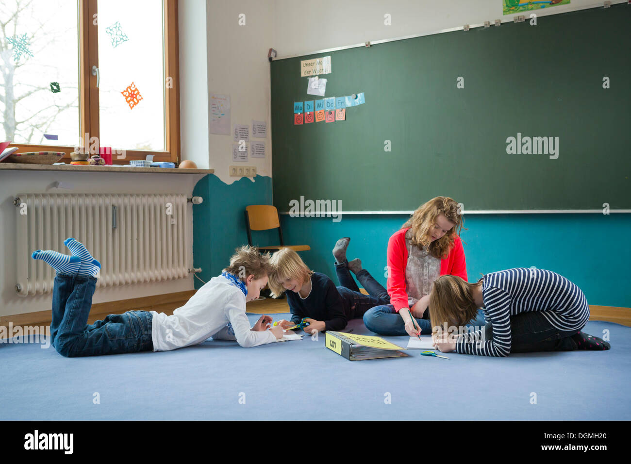 Students at an independant school sitting and lying to work on the ground, Aktive Schule Peterhausen, Petershausen Stock Photo