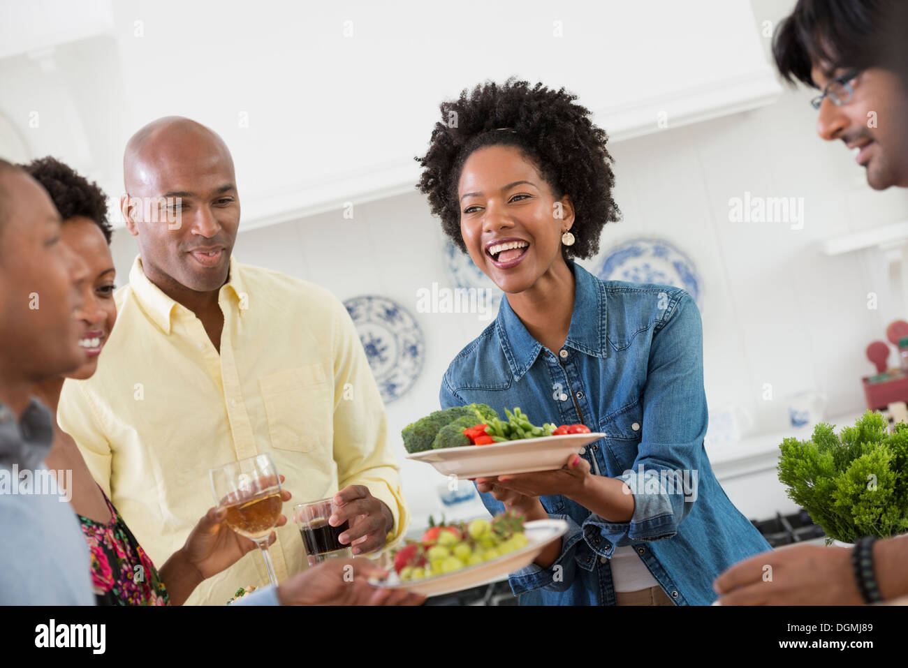 An informal office event. People handing plates of food across a buffet table. Stock Photo