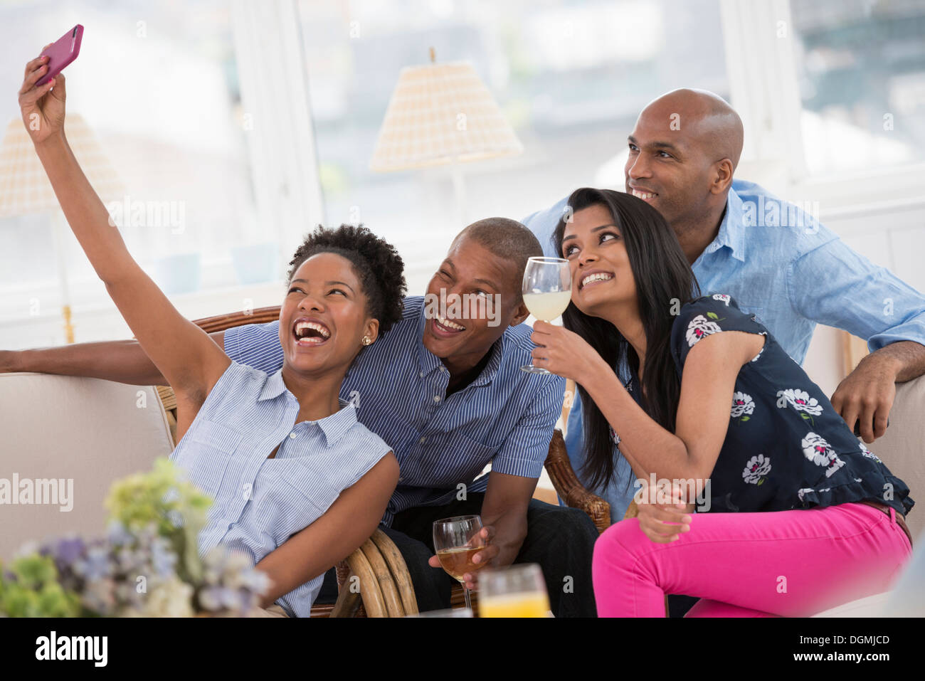 Office event. A woman taking a selfie of the group with a pink smart phone. Stock Photo