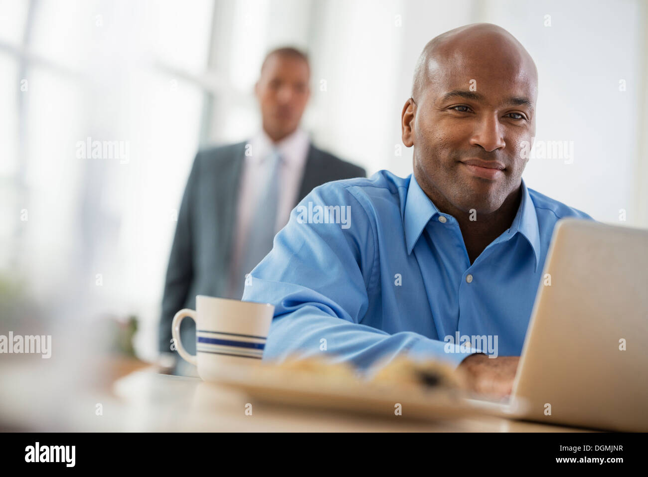 Office. A man sitting using a laptop. Stock Photo