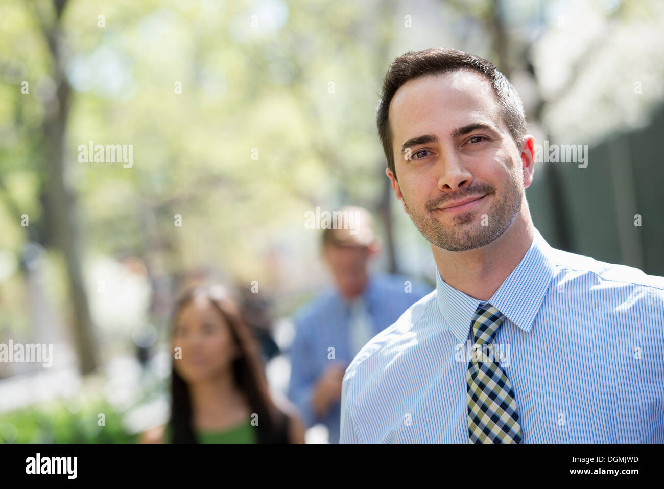 A small group of people, a businesswoman and two businessmen outdoors in the city. Stock Photo