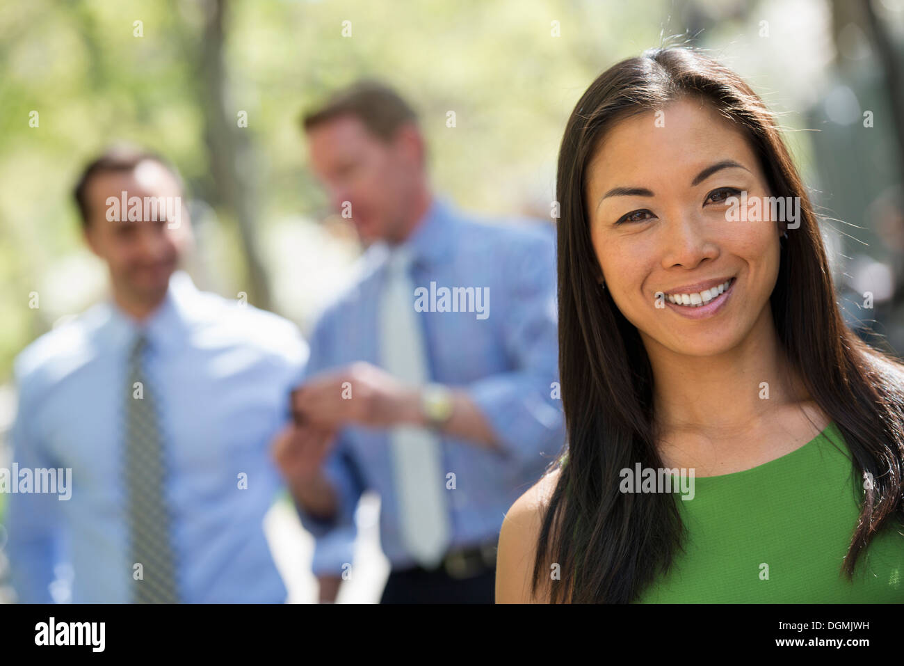 A small group of people, a businesswoman and two businessmen outdoors in the city. Stock Photo