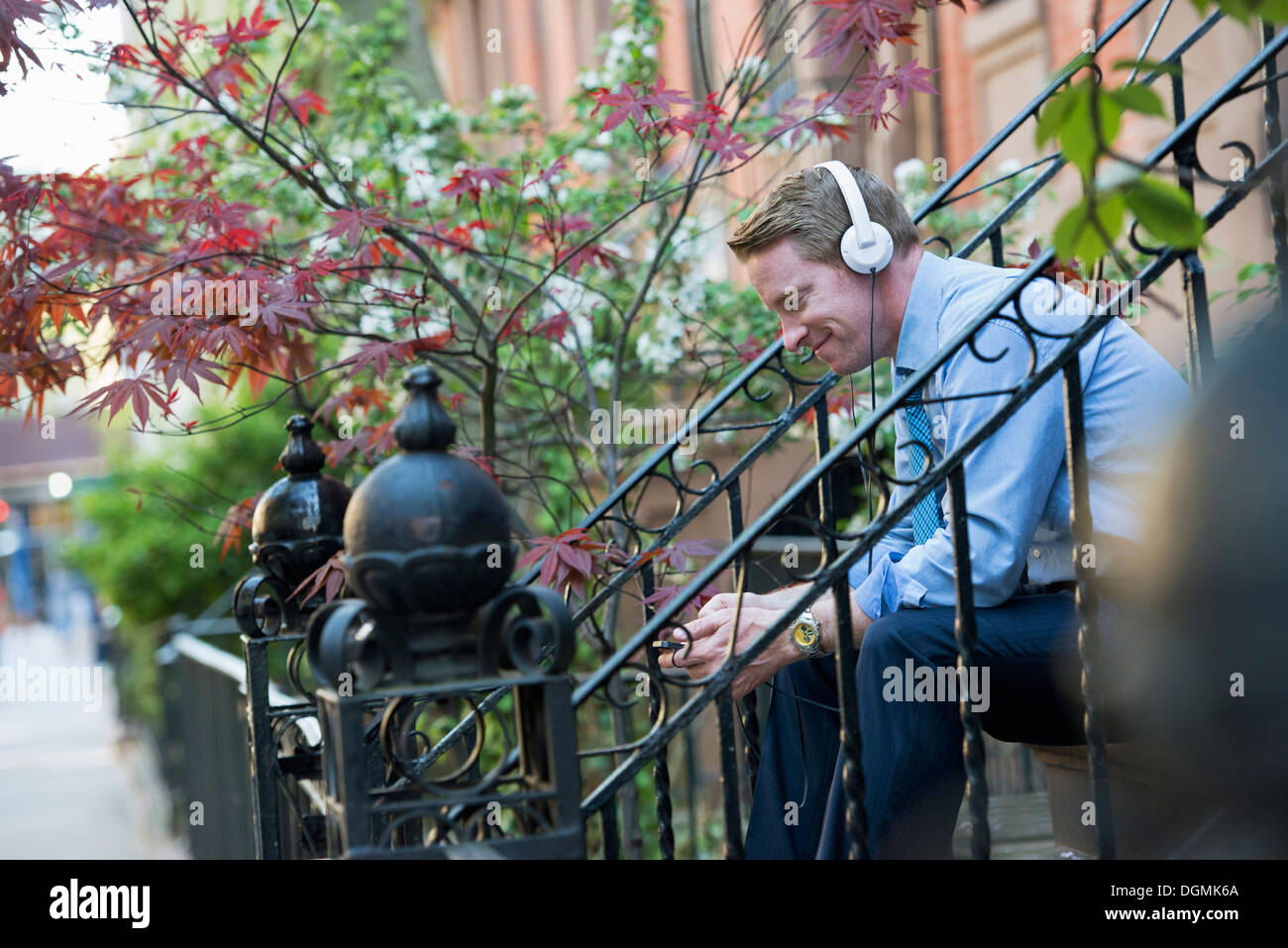 A man in a blue shirt wearing headphones and listening to a music player. Stock Photo