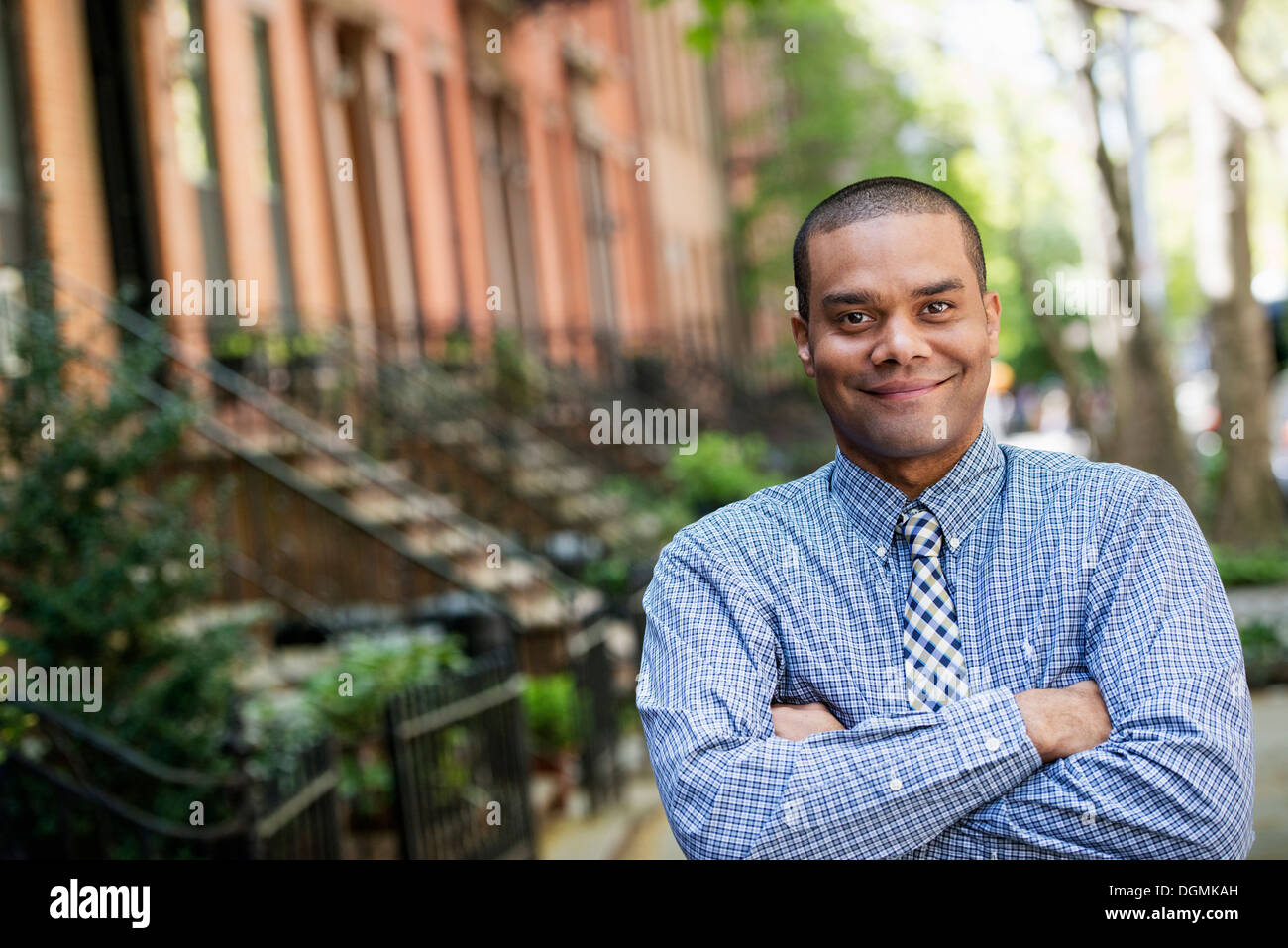 A man in a blue shirt and tie standing on a city street. Stock Photo